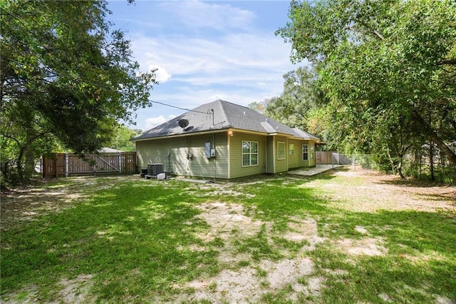 rear view of house featuring a fenced backyard, central air condition unit, and a yard