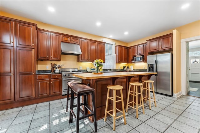 kitchen with a breakfast bar area, a kitchen island, stainless steel appliances, and light tile patterned floors