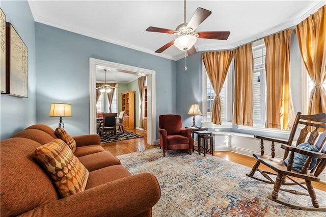 living area featuring crown molding, light hardwood / wood-style floors, and ceiling fan