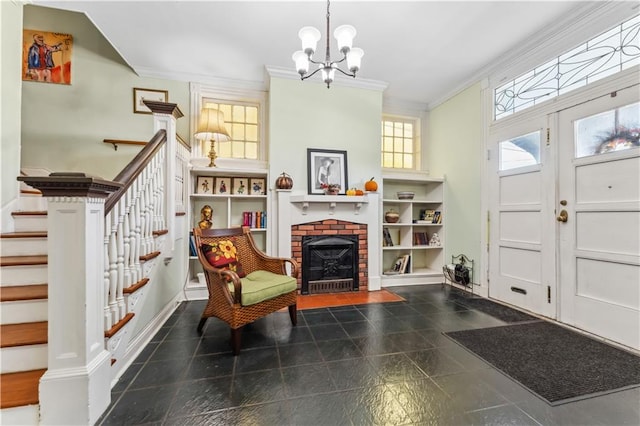 foyer entrance featuring crown molding, a notable chandelier, and a fireplace