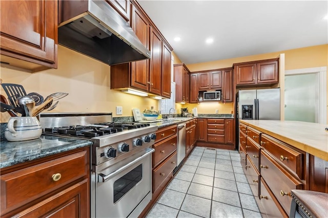 kitchen with stainless steel appliances, sink, dark stone counters, and light tile patterned floors