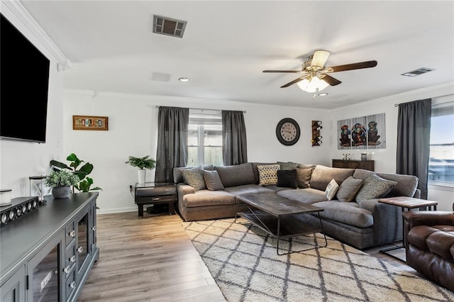 living room featuring ornamental molding, light hardwood / wood-style floors, and ceiling fan