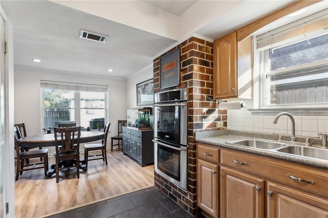 kitchen featuring visible vents, a sink, crown molding, double oven, and tasteful backsplash