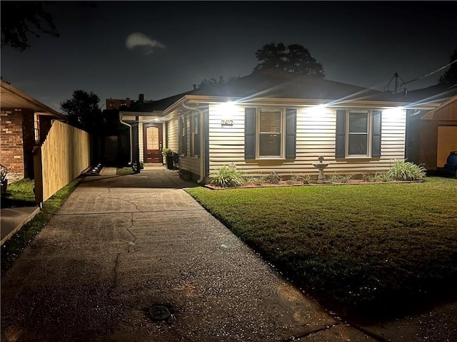 view of front of home featuring fence and a lawn