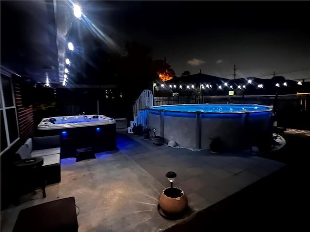 patio at night with fence and a fenced in pool