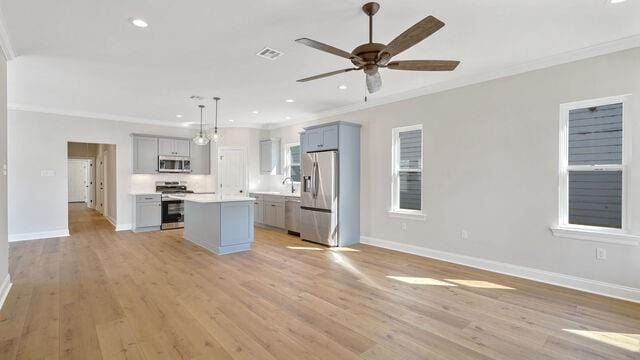 kitchen with light hardwood / wood-style flooring, stainless steel appliances, crown molding, a center island, and pendant lighting