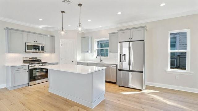 kitchen with gray cabinets, a kitchen island, stainless steel appliances, and light hardwood / wood-style floors