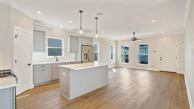 kitchen with a center island, gray cabinetry, stainless steel appliances, and pendant lighting