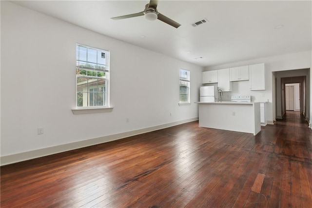 unfurnished living room with a wealth of natural light, sink, dark wood-type flooring, and ceiling fan