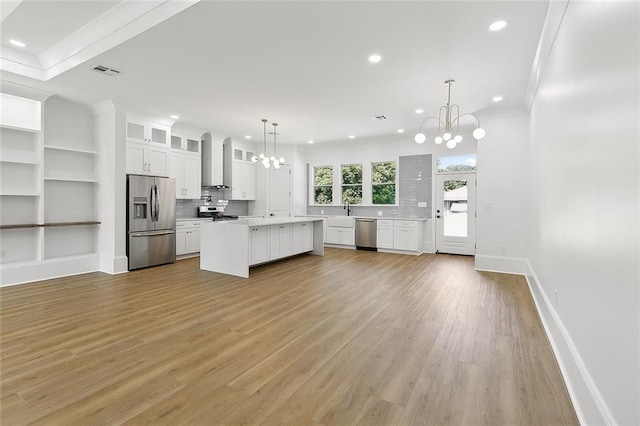 kitchen with pendant lighting, a center island, an inviting chandelier, white cabinets, and appliances with stainless steel finishes