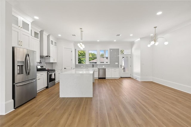 kitchen featuring white cabinetry, stainless steel appliances, backsplash, decorative light fixtures, and a kitchen island