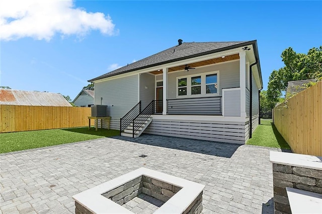 rear view of house with ceiling fan, a yard, central AC unit, a patio area, and an outdoor fire pit