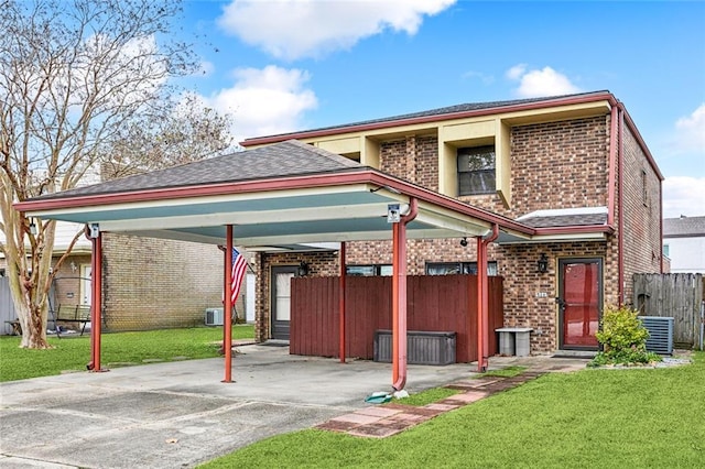 back of property featuring central AC unit, a carport, and a lawn