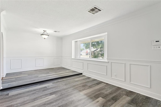 unfurnished room featuring crown molding, wood-type flooring, and a textured ceiling