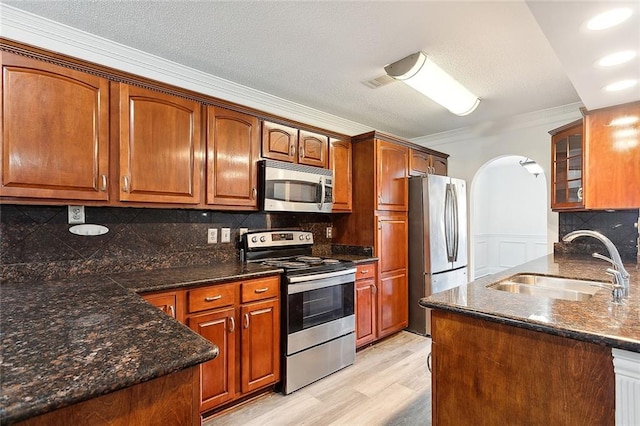 kitchen featuring tasteful backsplash, appliances with stainless steel finishes, light wood-type flooring, ornamental molding, and sink