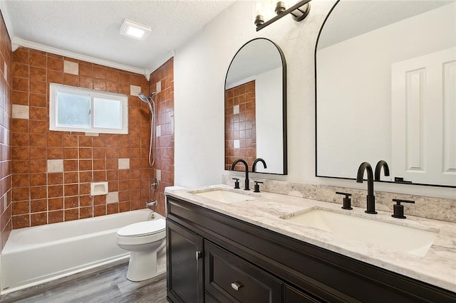 full bathroom with tiled shower / bath, vanity, hardwood / wood-style floors, and toilet