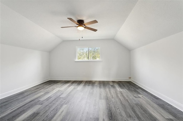 additional living space featuring lofted ceiling, a textured ceiling, dark wood-type flooring, and ceiling fan