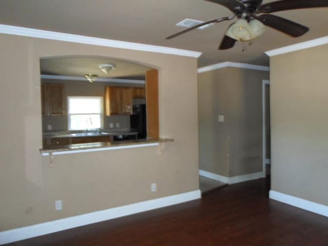 kitchen featuring sink, black fridge, ceiling fan, dark wood-type flooring, and crown molding