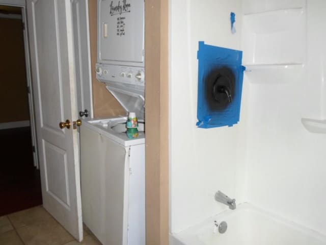 washroom with stacked washer and dryer and tile patterned floors