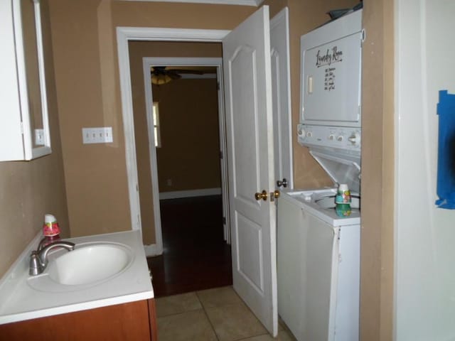 laundry room with light tile patterned flooring, sink, and stacked washer / dryer