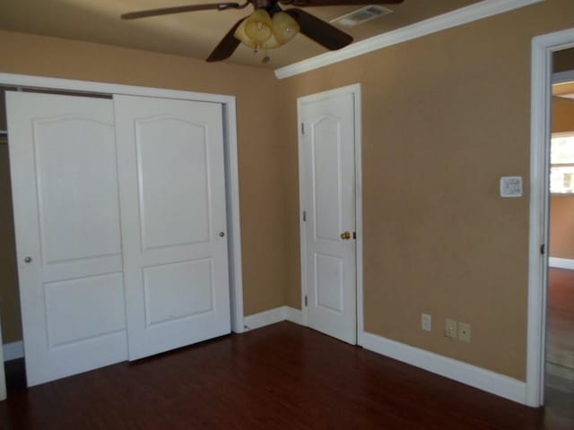 unfurnished bedroom featuring dark hardwood / wood-style flooring, crown molding, a closet, and ceiling fan