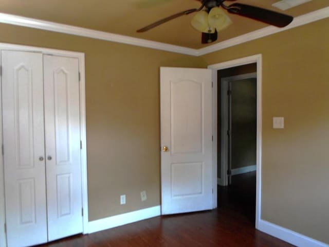 unfurnished bedroom with crown molding, a closet, dark wood-type flooring, and ceiling fan