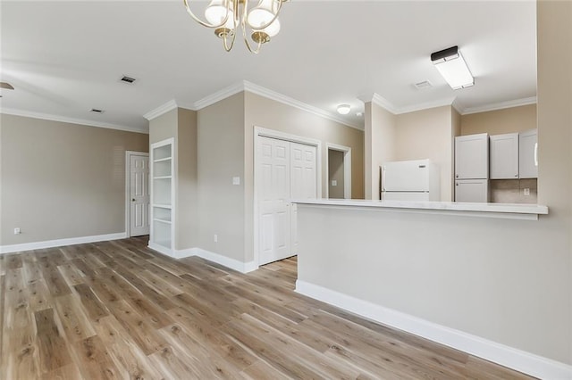 unfurnished living room with a chandelier, crown molding, and light hardwood / wood-style floors