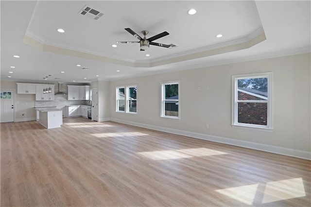 unfurnished living room with crown molding, a raised ceiling, and a wealth of natural light