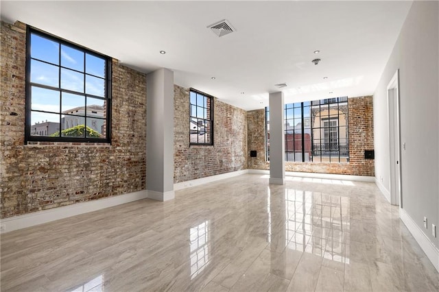 unfurnished room featuring plenty of natural light and brick wall