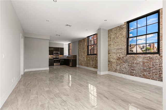 unfurnished living room with brick wall