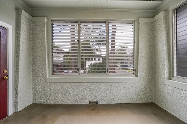 empty room with hardwood / wood-style flooring and crown molding