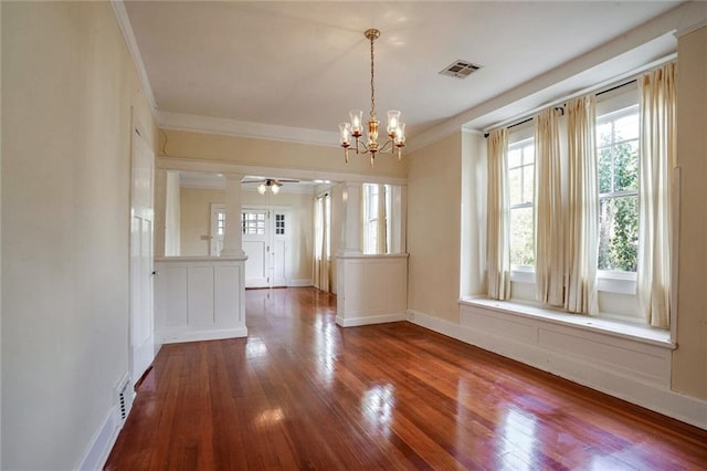 unfurnished dining area with ceiling fan with notable chandelier, wood-type flooring, and crown molding