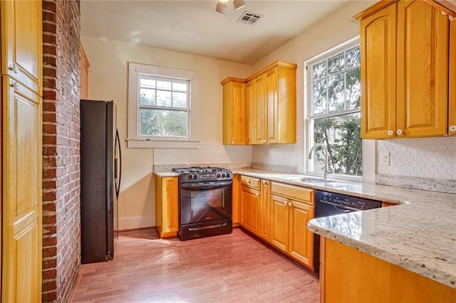 kitchen featuring black appliances, sink, decorative backsplash, light wood-type flooring, and light stone countertops