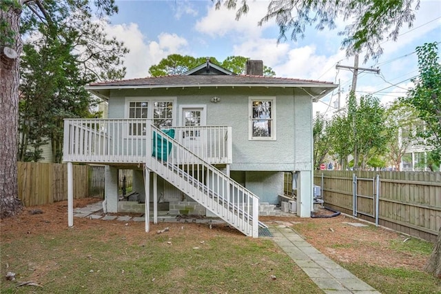 back of property with a lawn and a deck