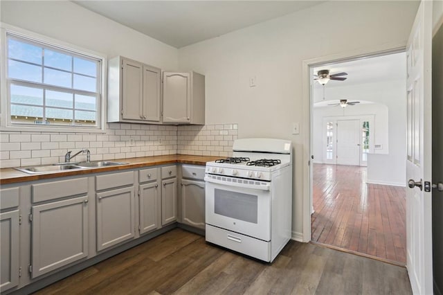 kitchen featuring gray cabinetry, sink, dark hardwood / wood-style flooring, white gas range, and decorative backsplash