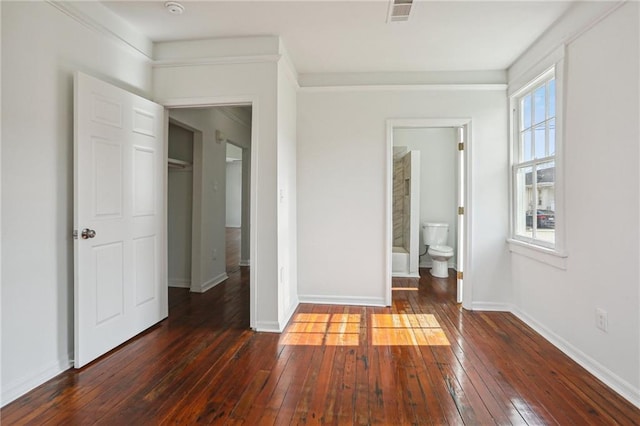 unfurnished bedroom with ensuite bathroom, crown molding, dark hardwood / wood-style floors, and a closet