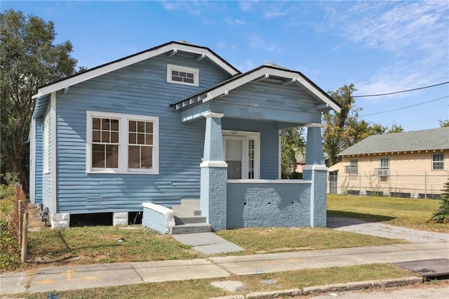 bungalow-style house with a front lawn and covered porch