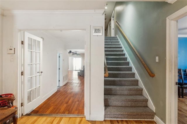 stairway with crown molding, baseboards, and wood finished floors