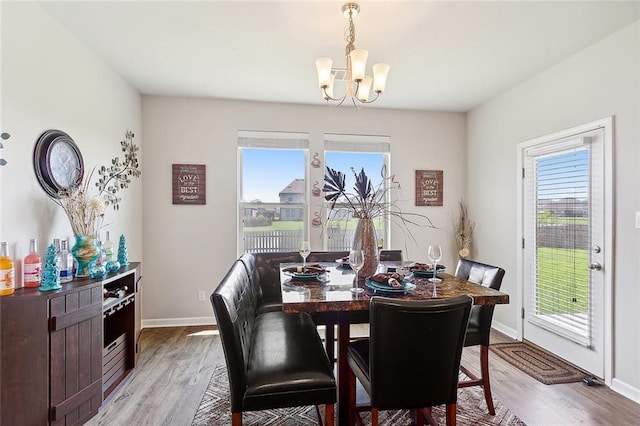 dining area featuring a wealth of natural light, a notable chandelier, and light wood-type flooring