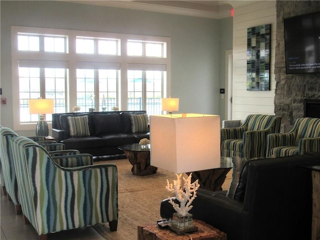 tiled living room featuring crown molding, a stone fireplace, and a healthy amount of sunlight