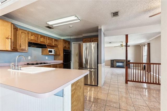 kitchen featuring a textured ceiling, stainless steel fridge, kitchen peninsula, and black double oven