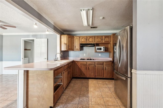 kitchen featuring kitchen peninsula, stainless steel refrigerator with ice dispenser, a textured ceiling, gas stovetop, and sink