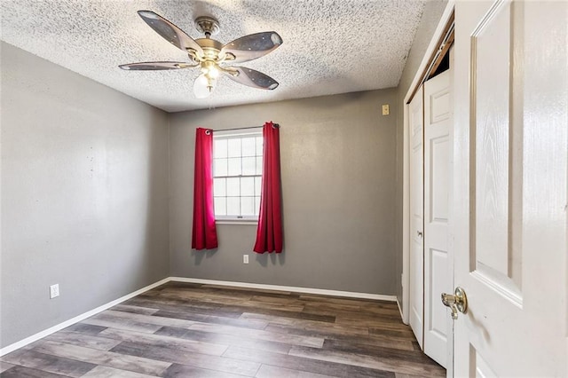 unfurnished bedroom with a textured ceiling, ceiling fan, dark wood-type flooring, and a closet