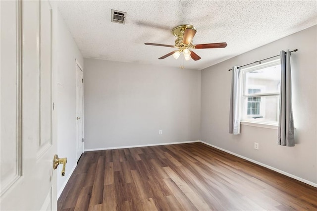 spare room with a textured ceiling, ceiling fan, and dark hardwood / wood-style floors