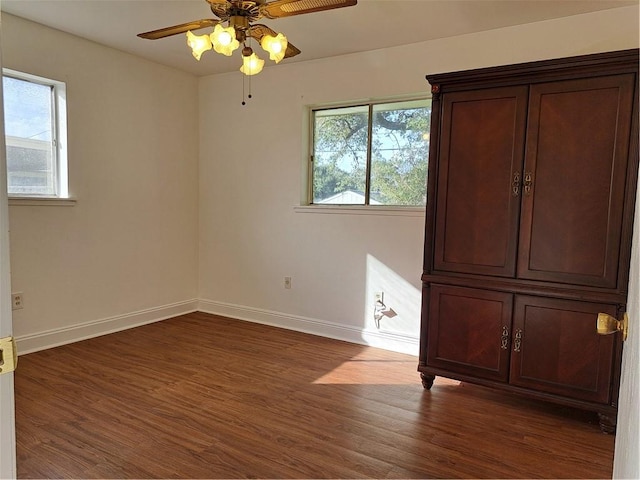 unfurnished room featuring dark wood-type flooring, ceiling fan, and a healthy amount of sunlight