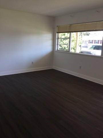 unfurnished room with dark wood-type flooring