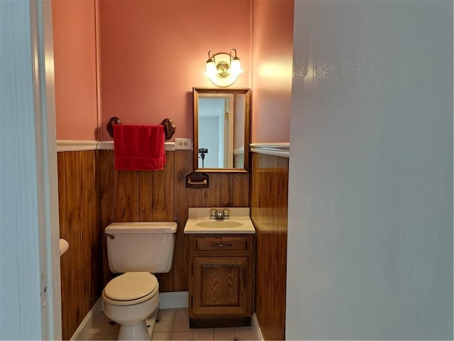 bathroom with vanity, toilet, wood walls, and tile patterned floors