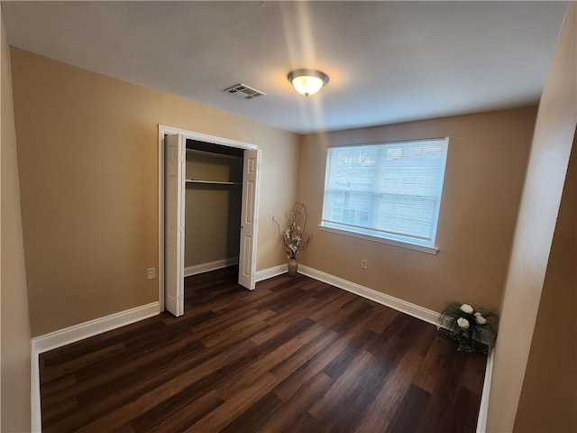 unfurnished bedroom featuring a closet and dark hardwood / wood-style flooring