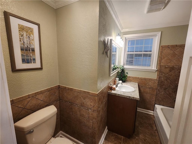 bathroom with a tub, toilet, tile walls, vanity, and crown molding