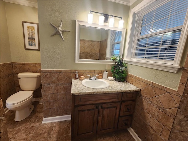 bathroom with vanity, toilet, tile walls, and ornamental molding